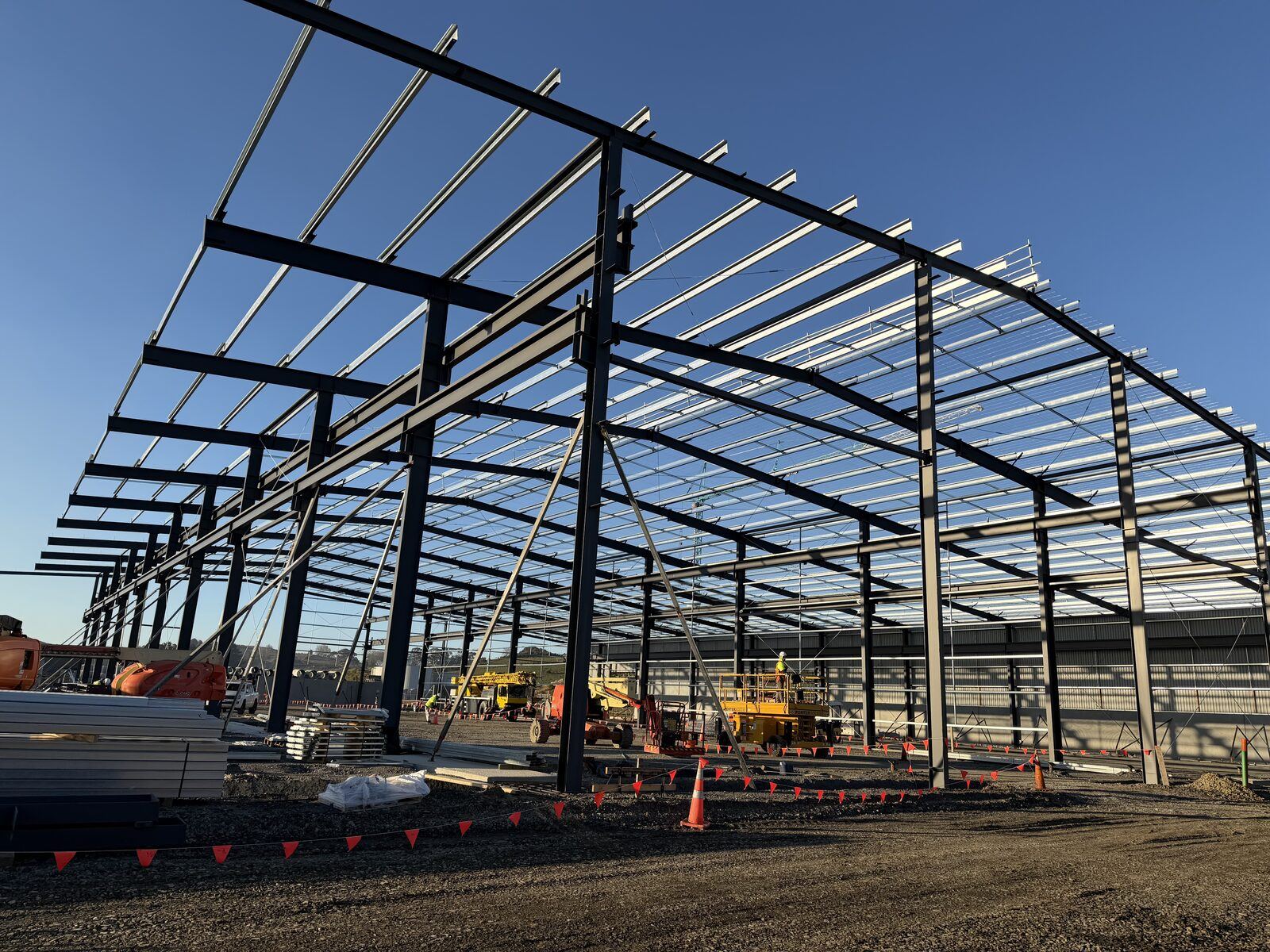Ground-level view through the steel portal frames at Hynds Pōkeno against a clear sky